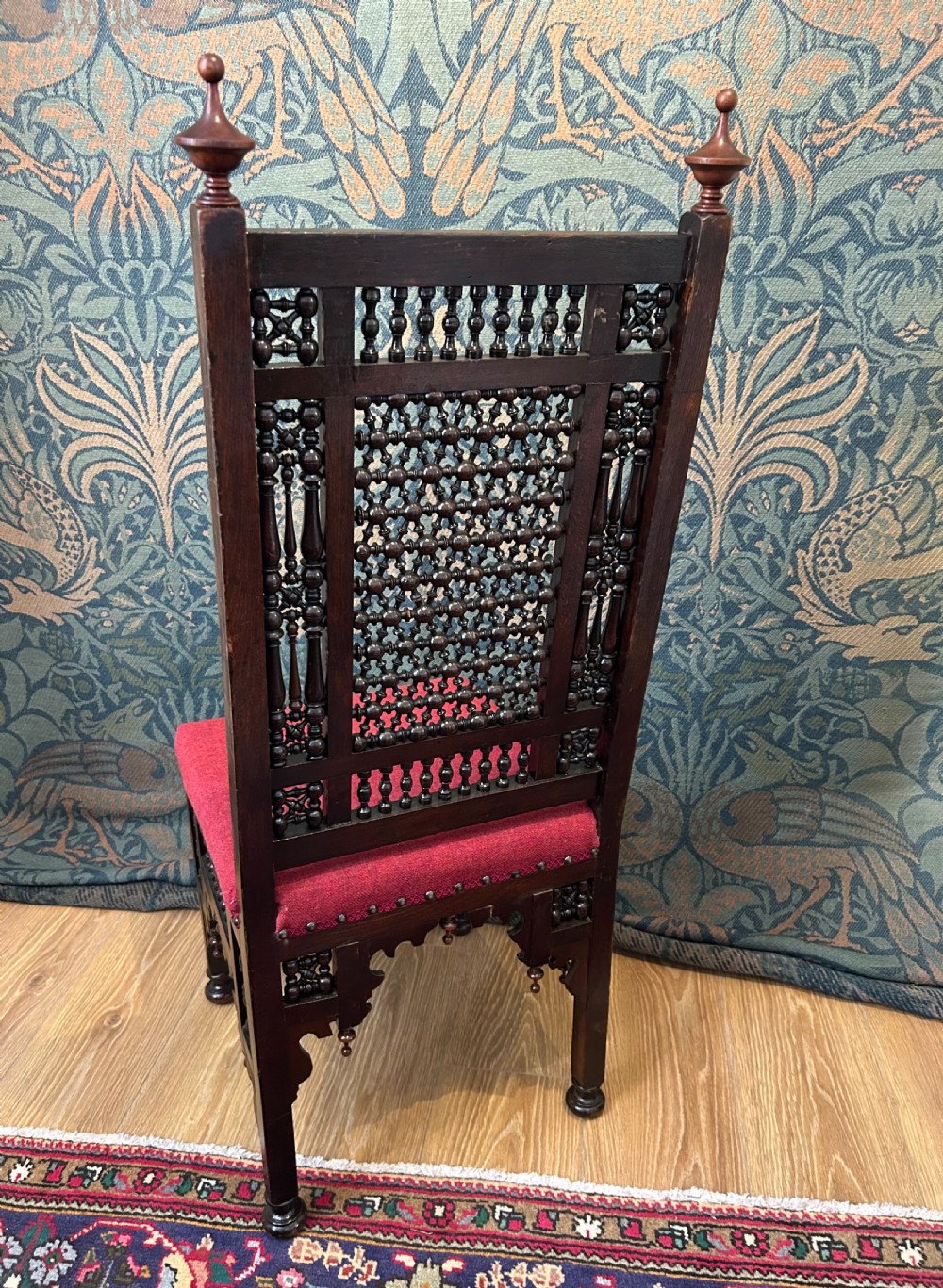 A pair of dark wood Cairene side chairs featuring turned bobbin mashrabiya latticework on the backrests and lower aprons, topped with corner finials and fitted with red wool upholstered seats. View X