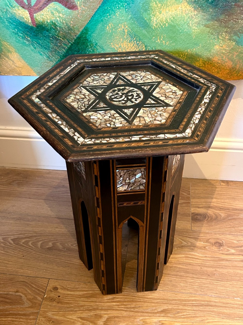 A hexagonal dark wood side table featuring intricate Mother-of-Pearl geometric inlays, a central calligraphic star motif, and arched cutout legs.