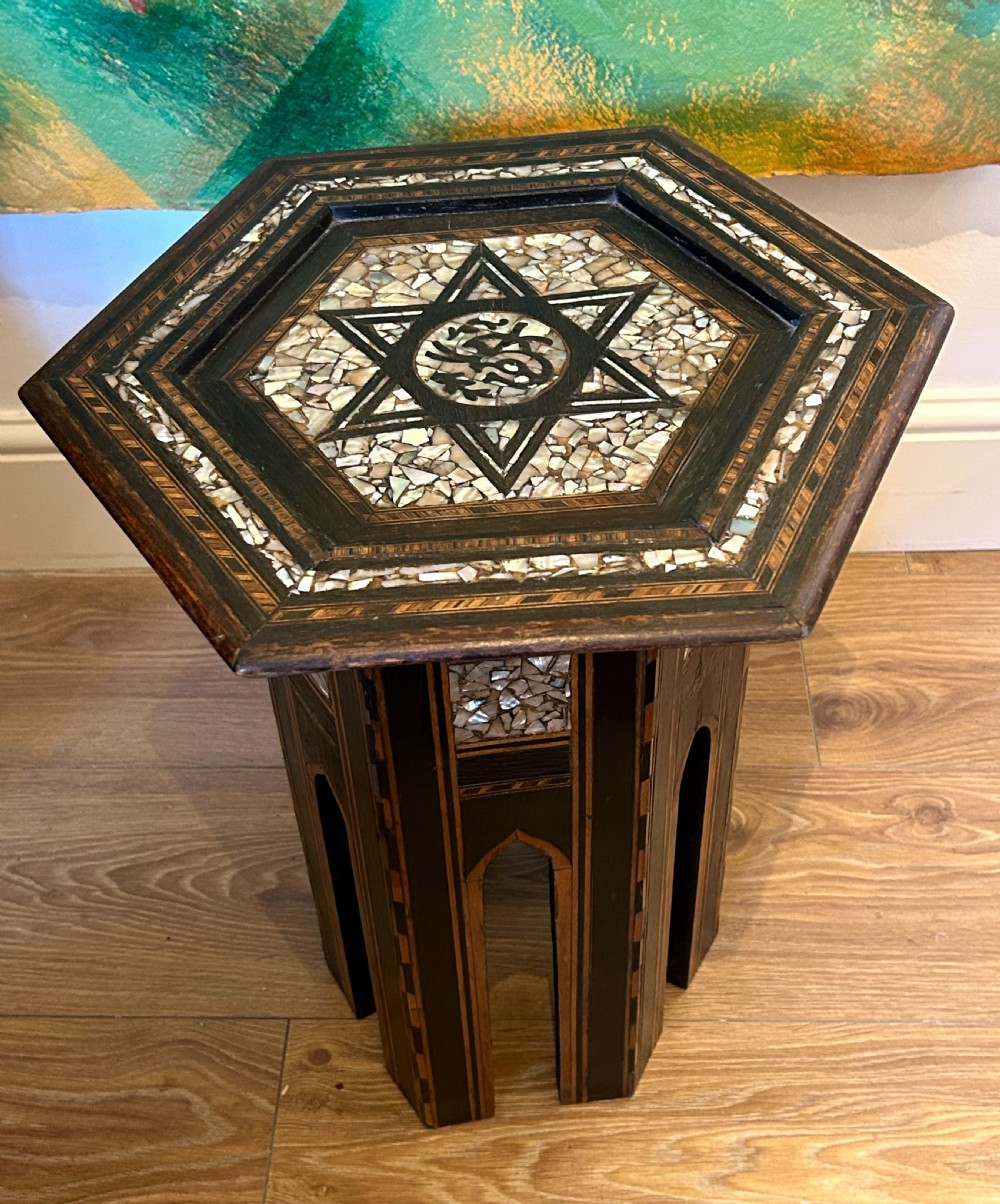 A hexagonal dark wood side table featuring intricate Mother-of-Pearl geometric inlays, a central calligraphic star motif, and arched cutout legs. View V