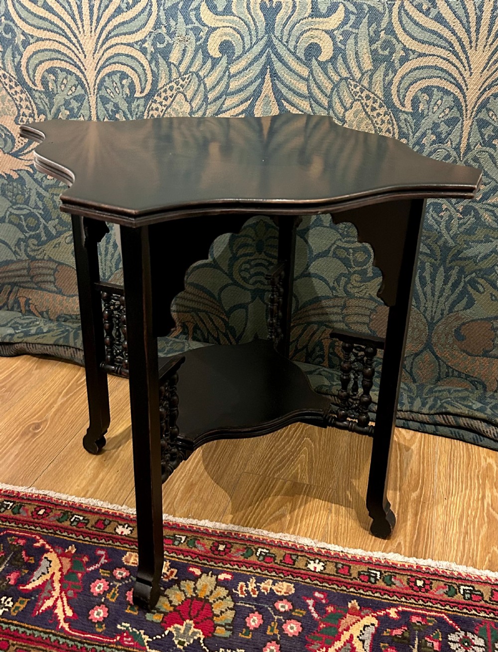 An ebonised wooden Anglo-Moorish occasional table featuring a shaped top, lower tier, and turned spindle gallery details. View III