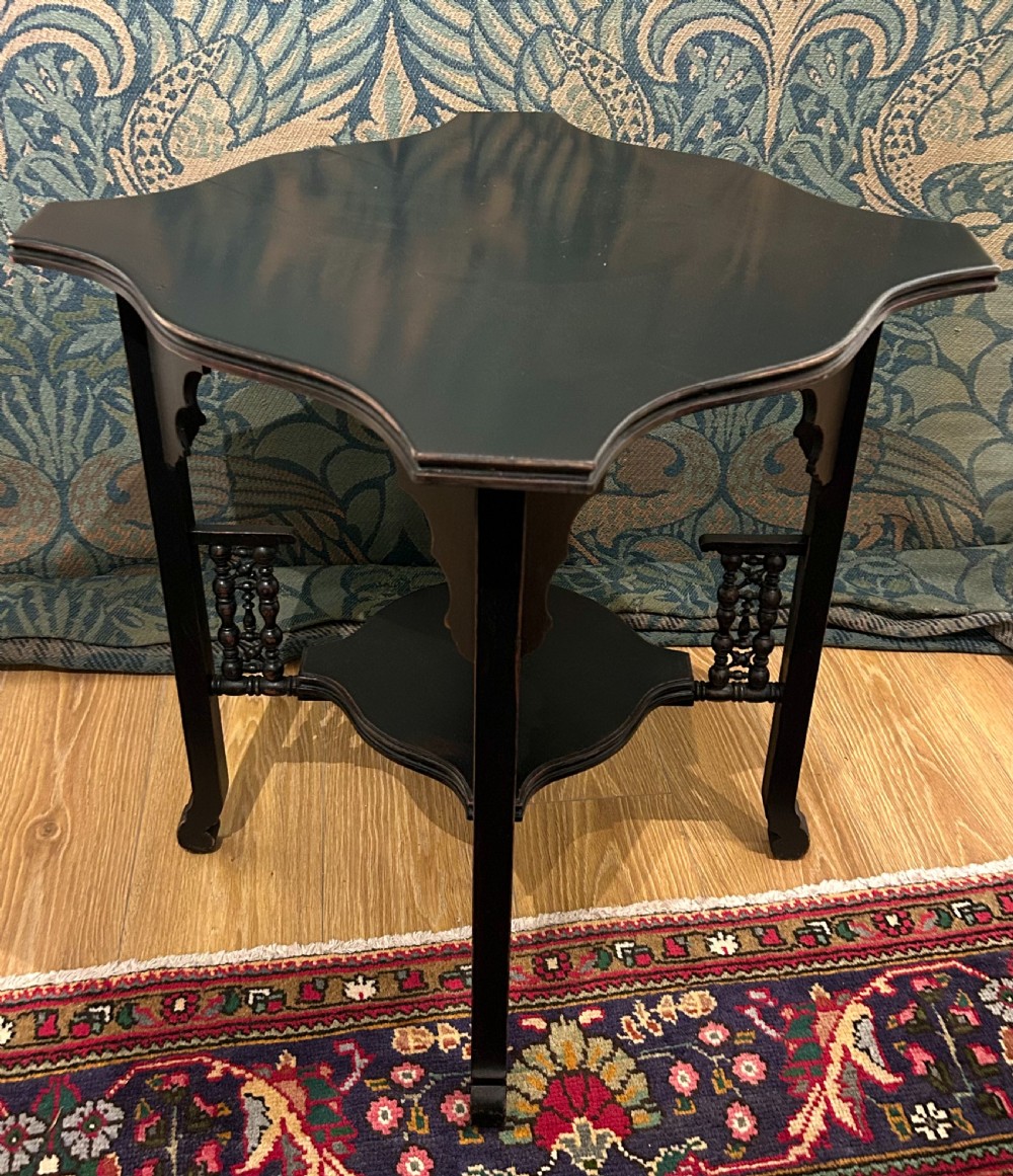 An ebonised wooden Anglo-Moorish occasional table featuring a shaped top, lower tier, and turned spindle gallery details. View IV