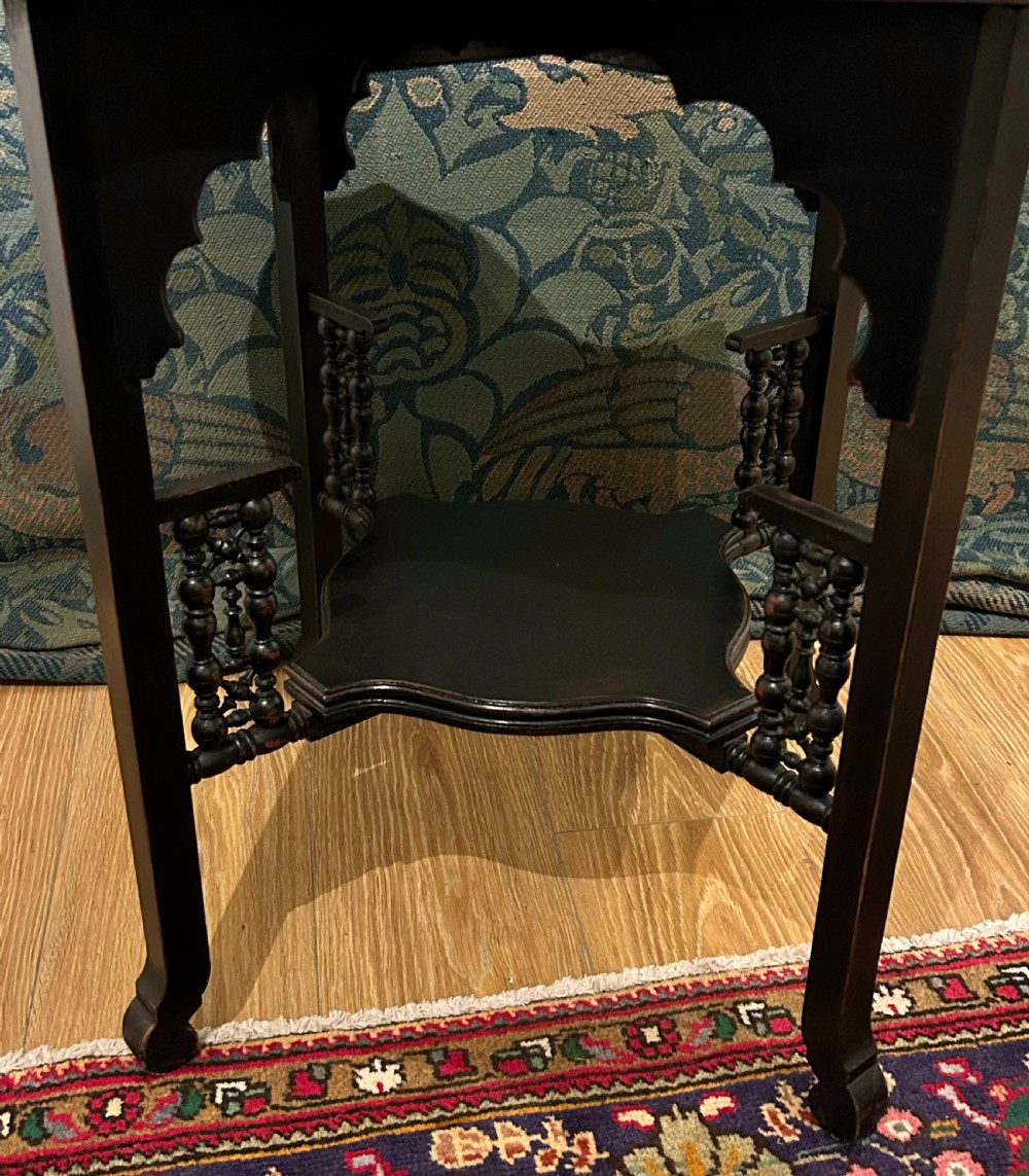 An ebonised wooden Anglo-Moorish occasional table featuring a shaped top, lower tier, and turned spindle gallery details. View V