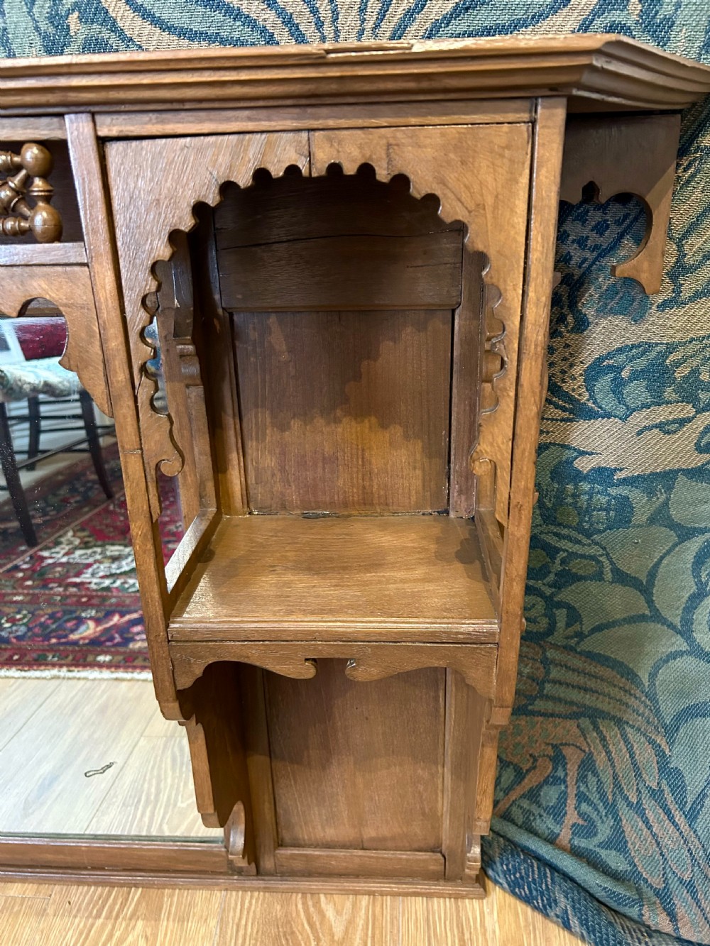 A carved wooden Moorish style overmantel mirror with a central glass panel, horseshoe arch side shelves, and a top turned spindle gallery. View VII