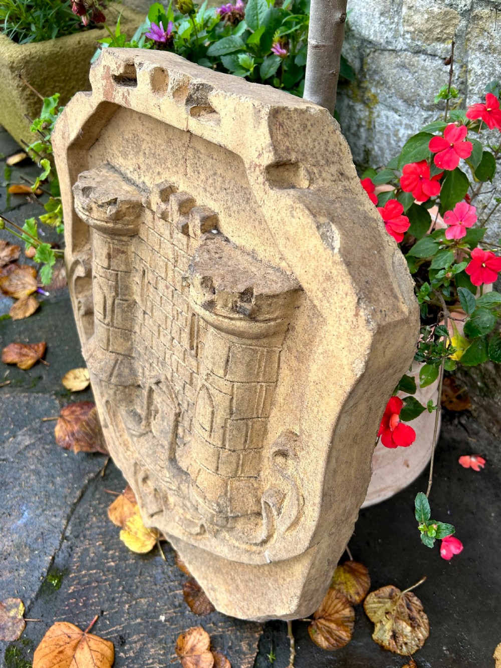 A carved buff stone armorial shield plaque featuring a relief depiction of a twin-towered castle gate with scrolled side details. View III