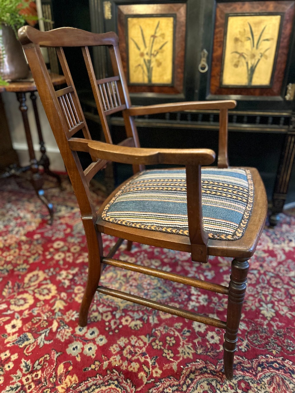 An Aesthetic Movement timber armchair with turned legs, spindle back details, curved armrests, and a striped woven fabric seat. View III