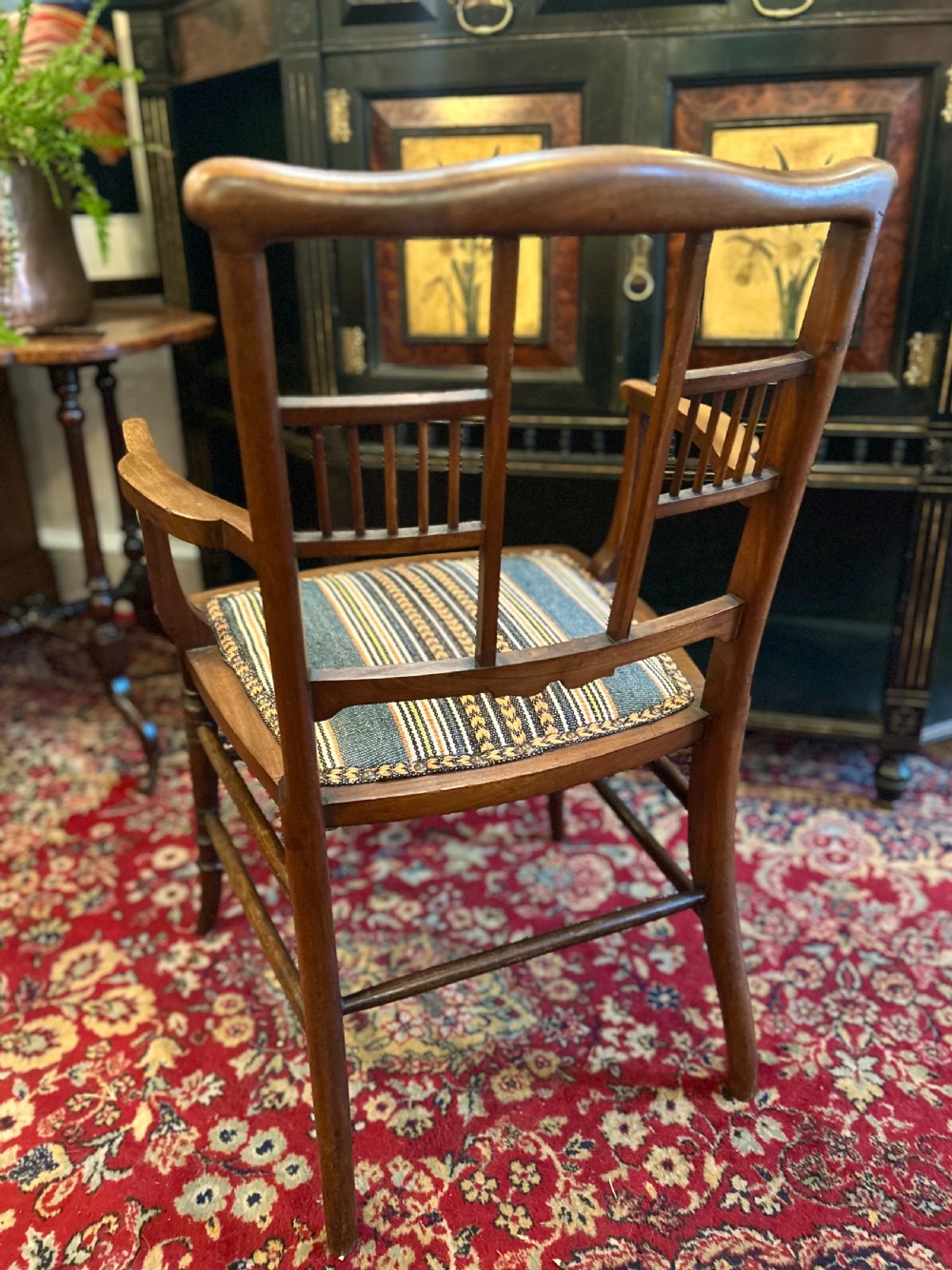 An Aesthetic Movement timber armchair with turned legs, spindle back details, curved armrests, and a striped woven fabric seat. View IV