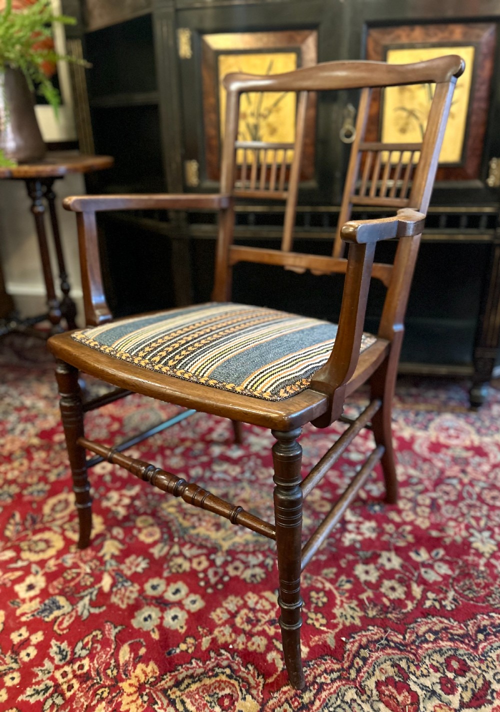 An Aesthetic Movement timber armchair with turned legs, spindle back details, curved armrests, and a striped woven fabric seat. View VI
