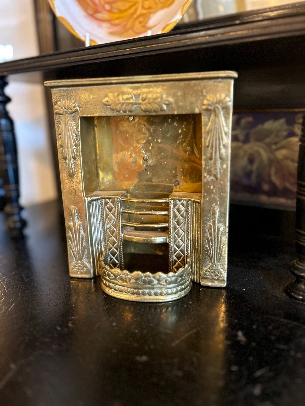 A Victorian brass tradesmans sample fireplace featuring embossed foliage details, a central grate, and a curved fender.