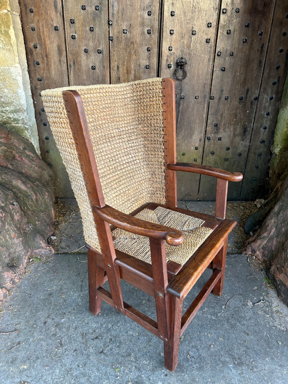 An antique Scottish Orkney armchair featuring a dark oak wood frame, scrolled arms, a drop-in rush seat, and a tall woven straw backrest. View II