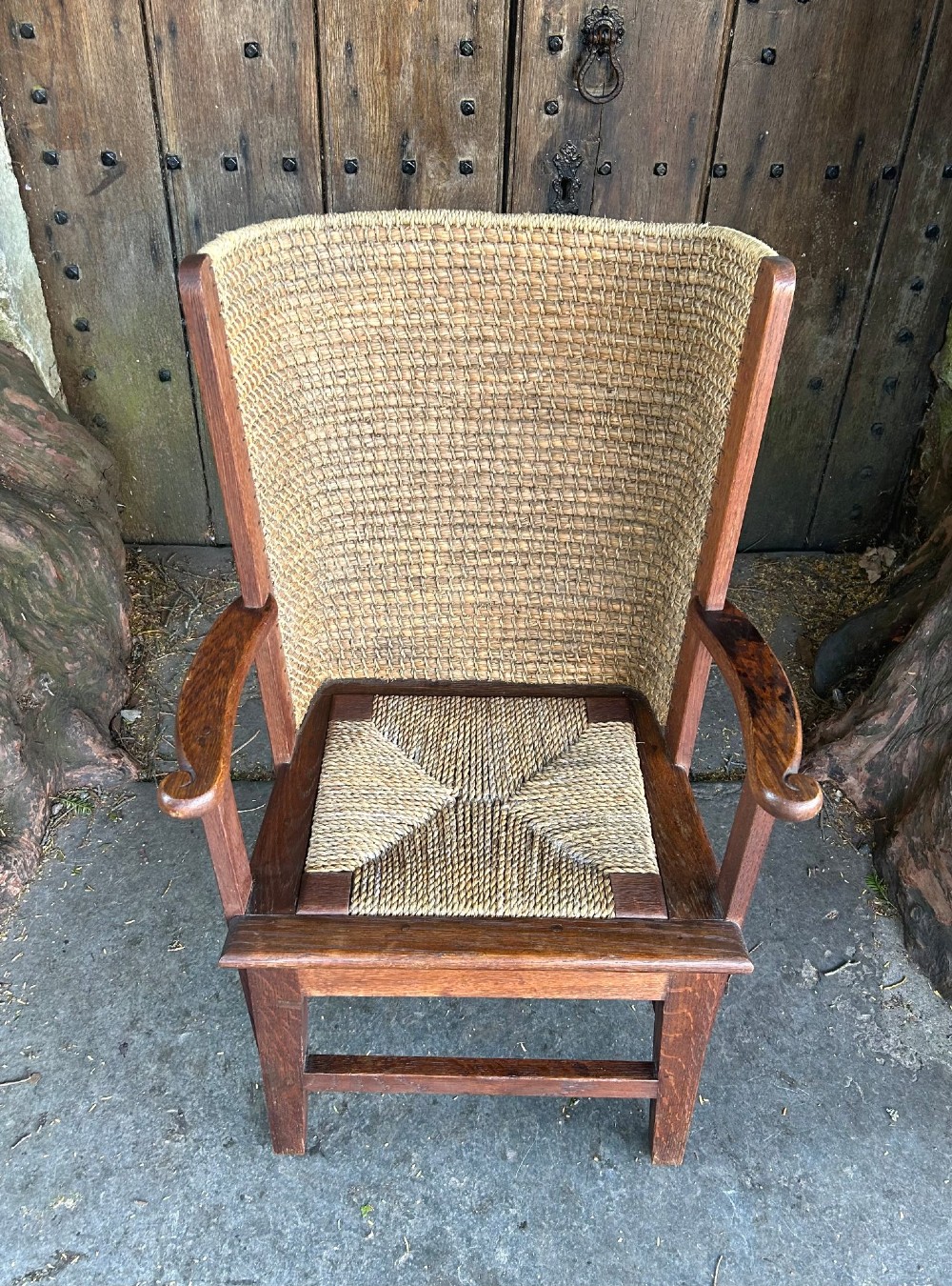 An antique Scottish Orkney armchair featuring a dark oak wood frame, scrolled arms, a drop-in rush seat, and a tall woven straw backrest. View V