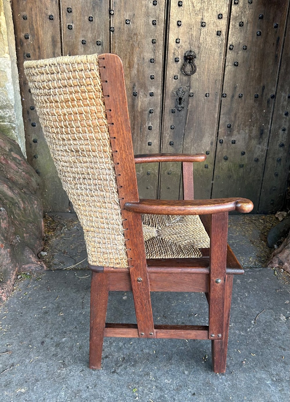 An antique Scottish Orkney armchair featuring a dark oak wood frame, scrolled arms, a drop-in rush seat, and a tall woven straw backrest. View VI