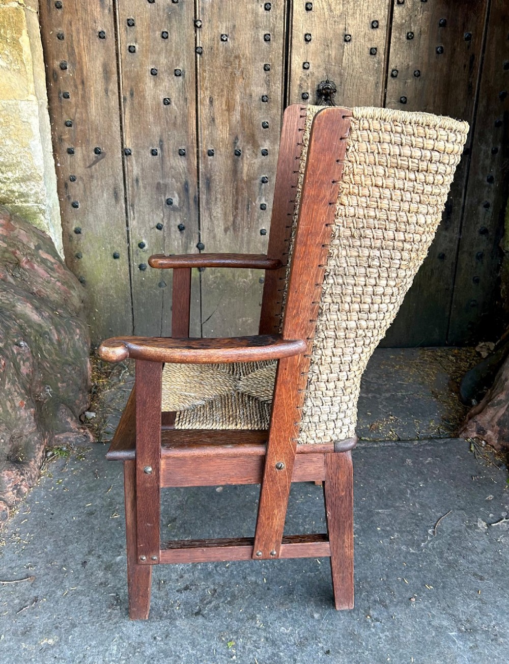 An antique Scottish Orkney armchair featuring a dark oak wood frame, scrolled arms, a drop-in rush seat, and a tall woven straw backrest. View VII