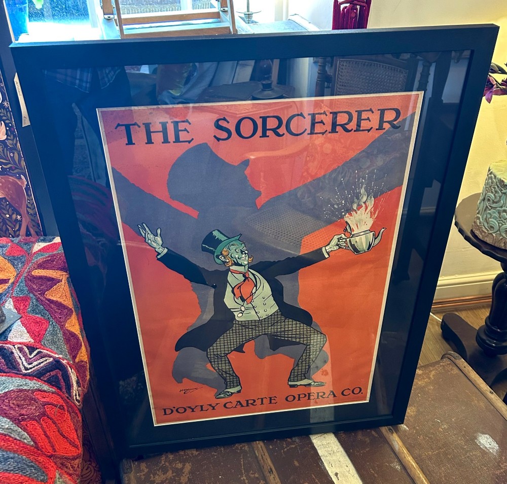 A framed vintage 1919 theatre poster for The Sorcerer by the DOyly Carte Opera Company featuring a stylised figure with a top hat holding a steaming teapot against a bold orange and black background.