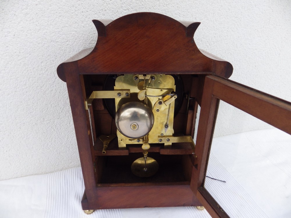 A carved mahogany English double fusee bracket clock featuring a circular cream dial with Roman numerals signed Osborn Bognor. View VI