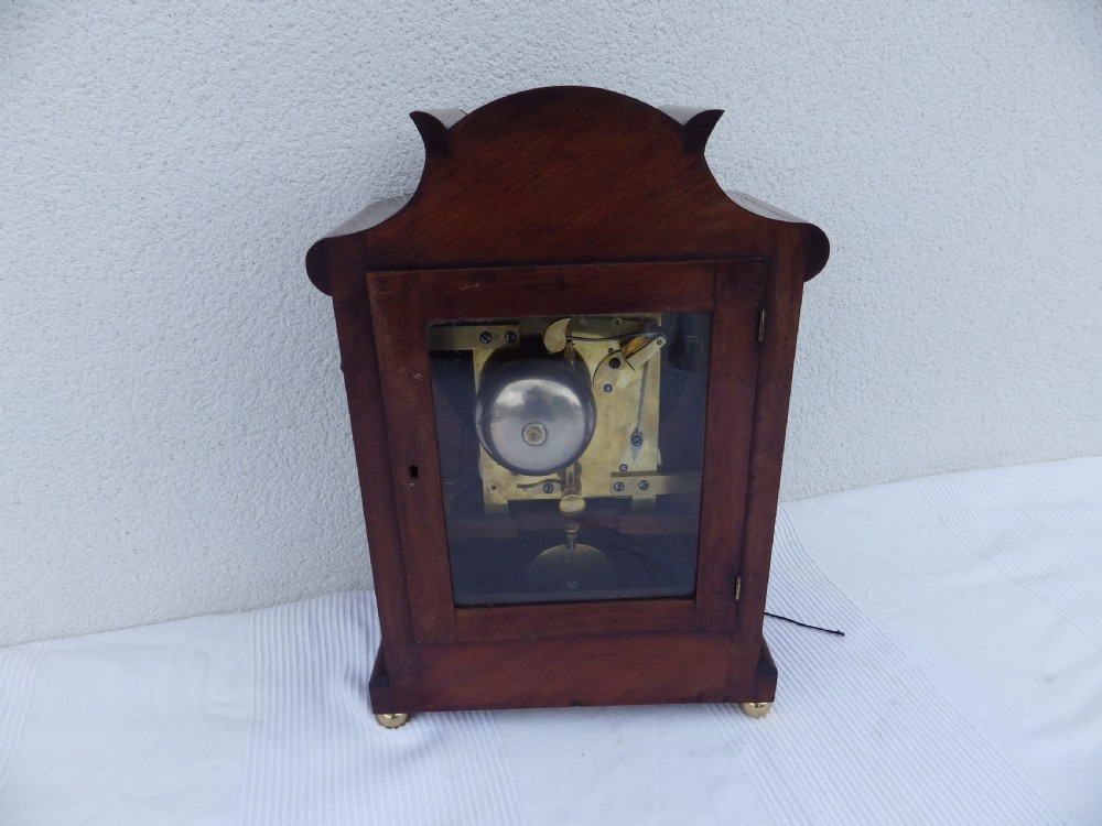 A carved mahogany English double fusee bracket clock featuring a circular cream dial with Roman numerals signed Osborn Bognor. View VII
