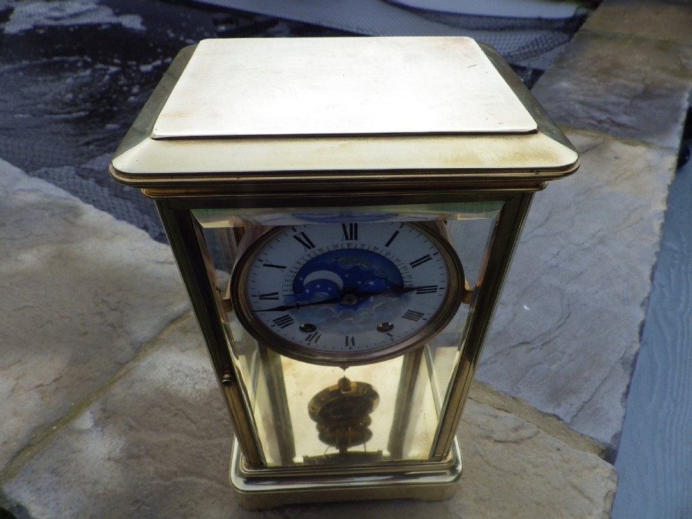 An antique brass four-glass regulator mantel clock featuring a white enamel dial with Roman numerals and an integrated blue moon-phase display. View II