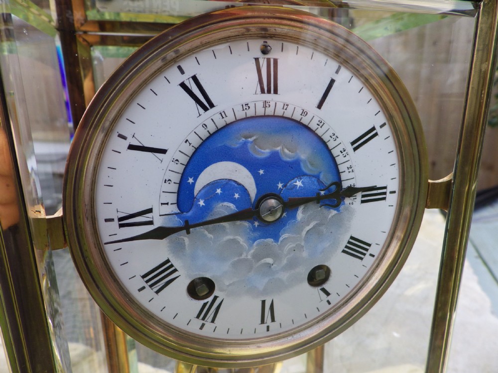 An antique brass four-glass regulator mantel clock featuring a white enamel dial with Roman numerals and an integrated blue moon-phase display. View IV