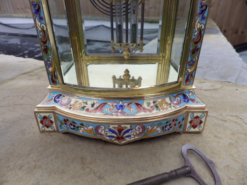 A late 19th-century French four-glass mantel clock featuring a brass frame, curved bow-front glass panel, polychrome champleve enamel borders, and a white porcelain dial with blue Arabic numerals. View II