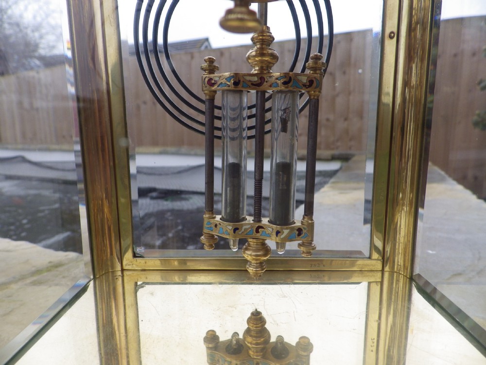 A late 19th-century French four-glass mantel clock featuring a brass frame, curved bow-front glass panel, polychrome champleve enamel borders, and a white porcelain dial with blue Arabic numerals. View IV