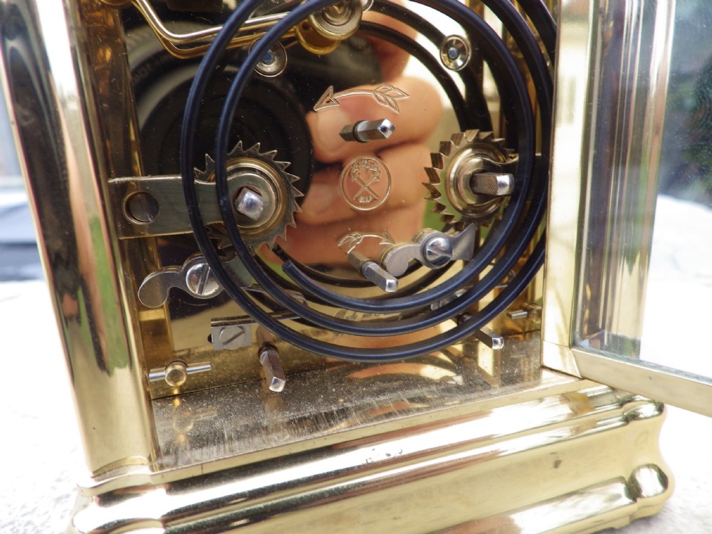 A polished brass LEpee carriage clock featuring bevelled glass panels, a white dial with Roman numerals, a moon phase aperture, and three subsidiary calendar dials. View VI
