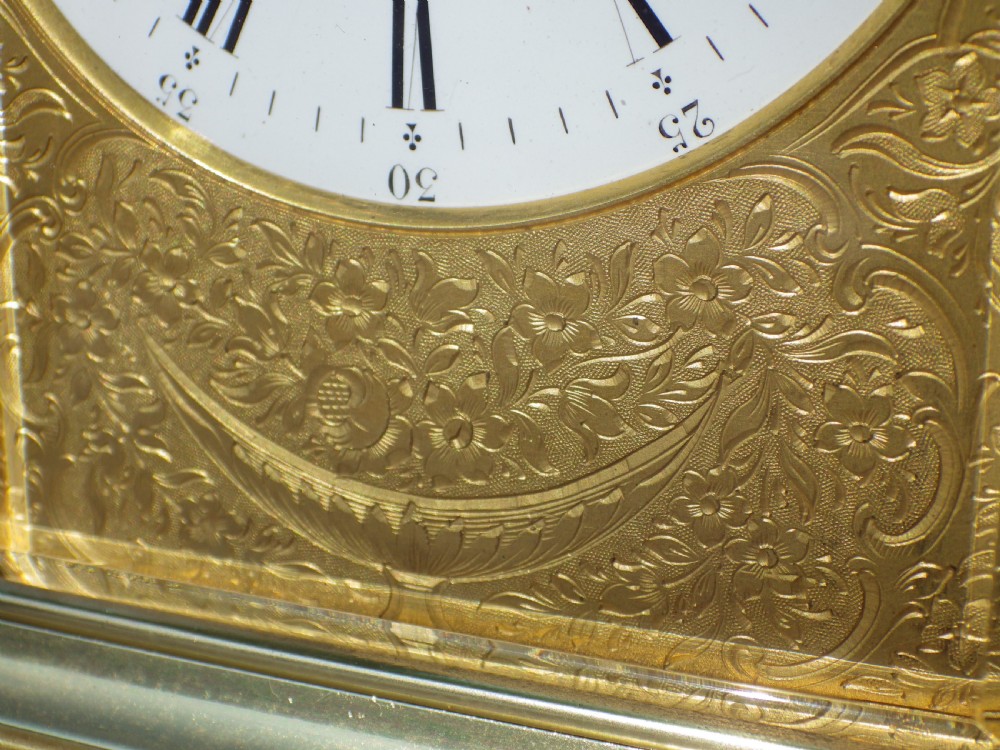 A French gilt brass giant repeating carriage clock featuring a white enamel dial with Roman numerals, an engraved brass mask, bevelled glass panels, and a hinged top handle. View VIII