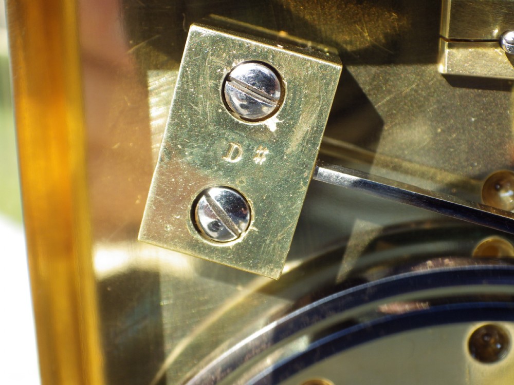 A French gilt brass giant repeating carriage clock featuring a white enamel dial with Roman numerals, an engraved brass mask, bevelled glass panels, and a hinged top handle. View X