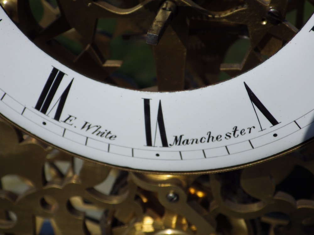 An antique Victorian brass skeleton clock featuring exposed internal mechanical gearing, a top-mounted bell, an enamel chapter ring with Roman numerals, and a white marble base. View III