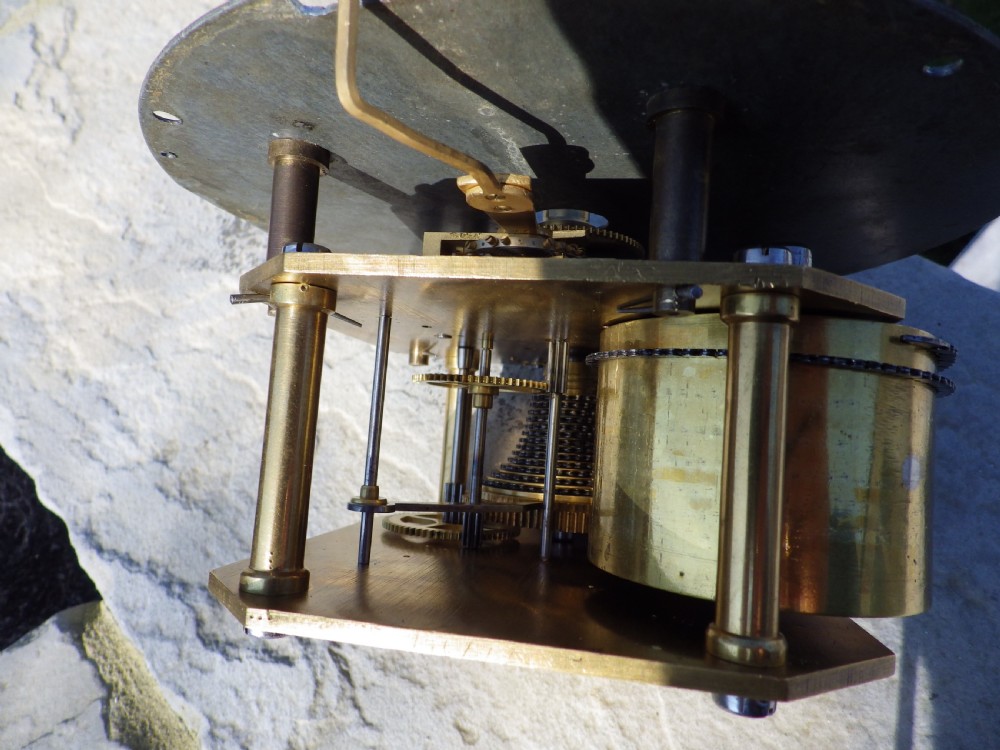 A circular brass ship clock featuring a white dial marked Prescot Clock Co with black Roman numerals and spade hands. View V