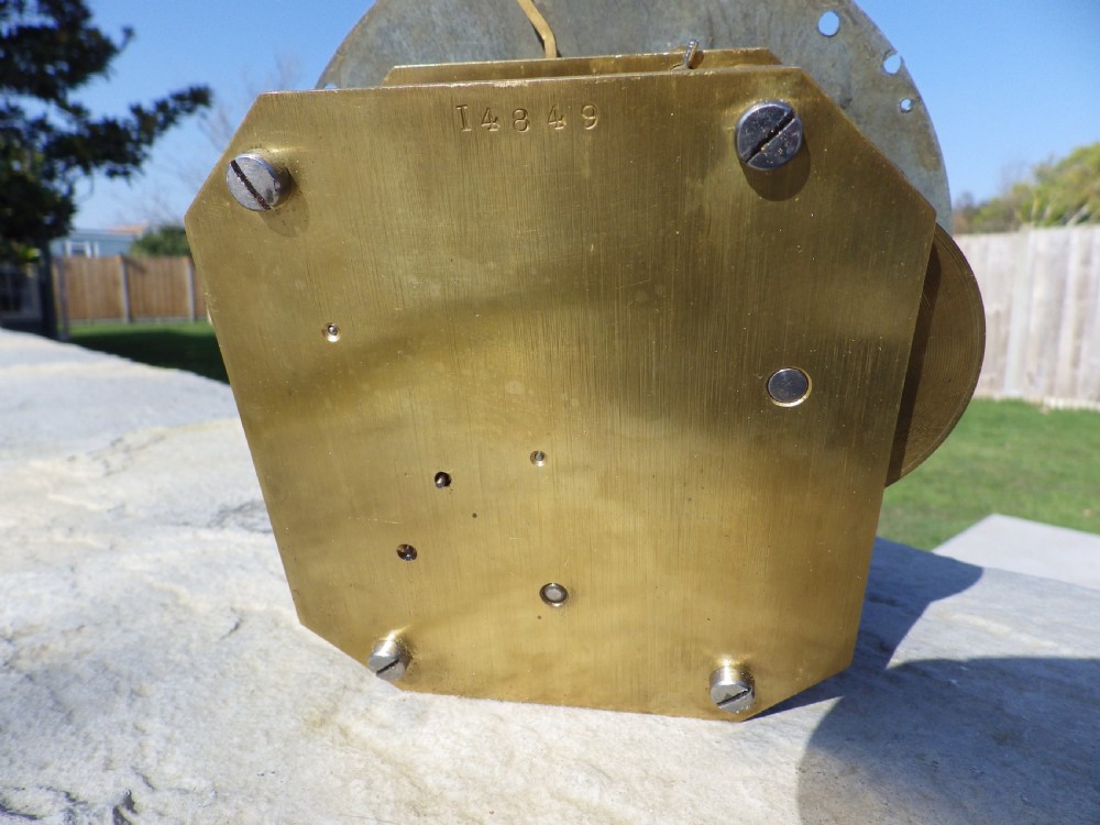 A circular brass ship clock featuring a white dial marked Prescot Clock Co with black Roman numerals and spade hands. View VI