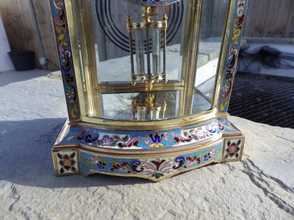 A late nineteenth-century French bow-fronted crystal regulator clock featuring gilt brass casing, polychrome enamel floral decoration, glass side panels, and a visible pendulum. View II
