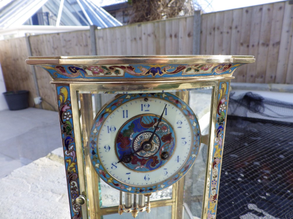 A late nineteenth-century French bow-fronted crystal regulator clock featuring gilt brass casing, polychrome enamel floral decoration, glass side panels, and a visible pendulum. View III