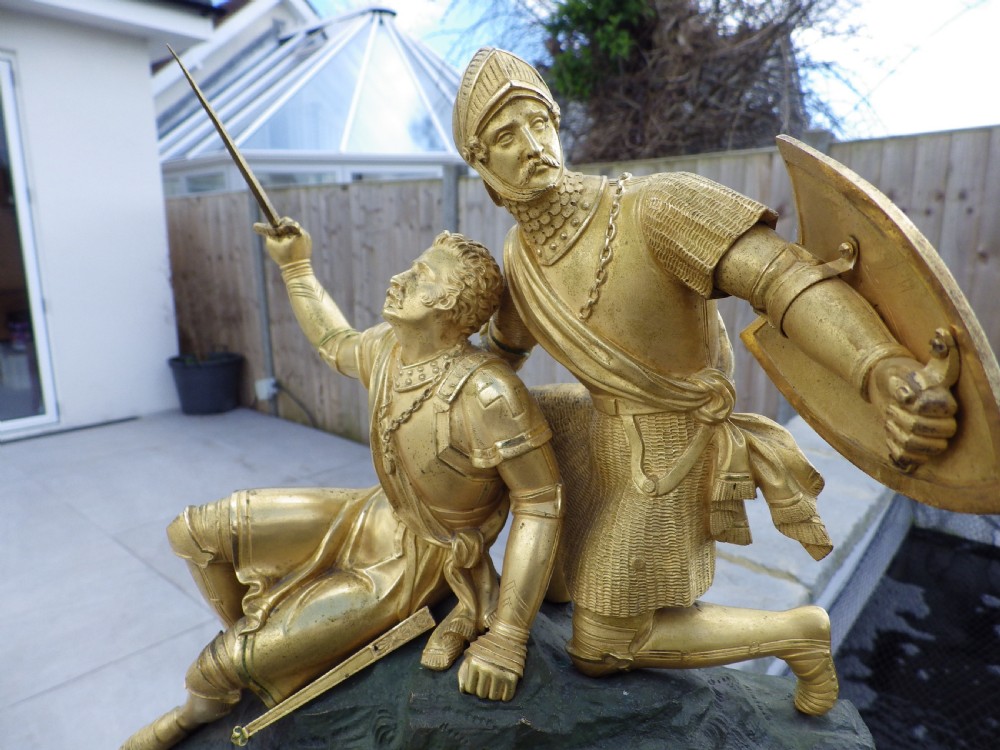 An antique French Empire gilt and patinated bronze mantel clock featuring sculpted figures of medieval soldiers above an ornamented base. View II