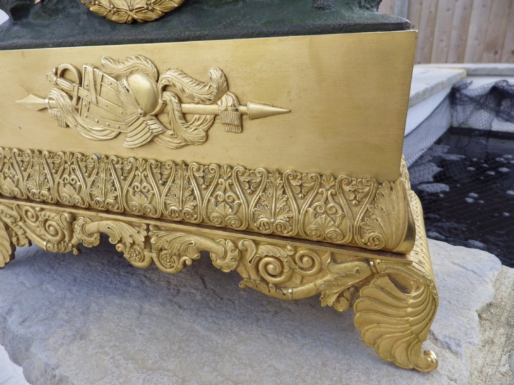 An antique French Empire gilt and patinated bronze mantel clock featuring sculpted figures of medieval soldiers above an ornamented base. View IV