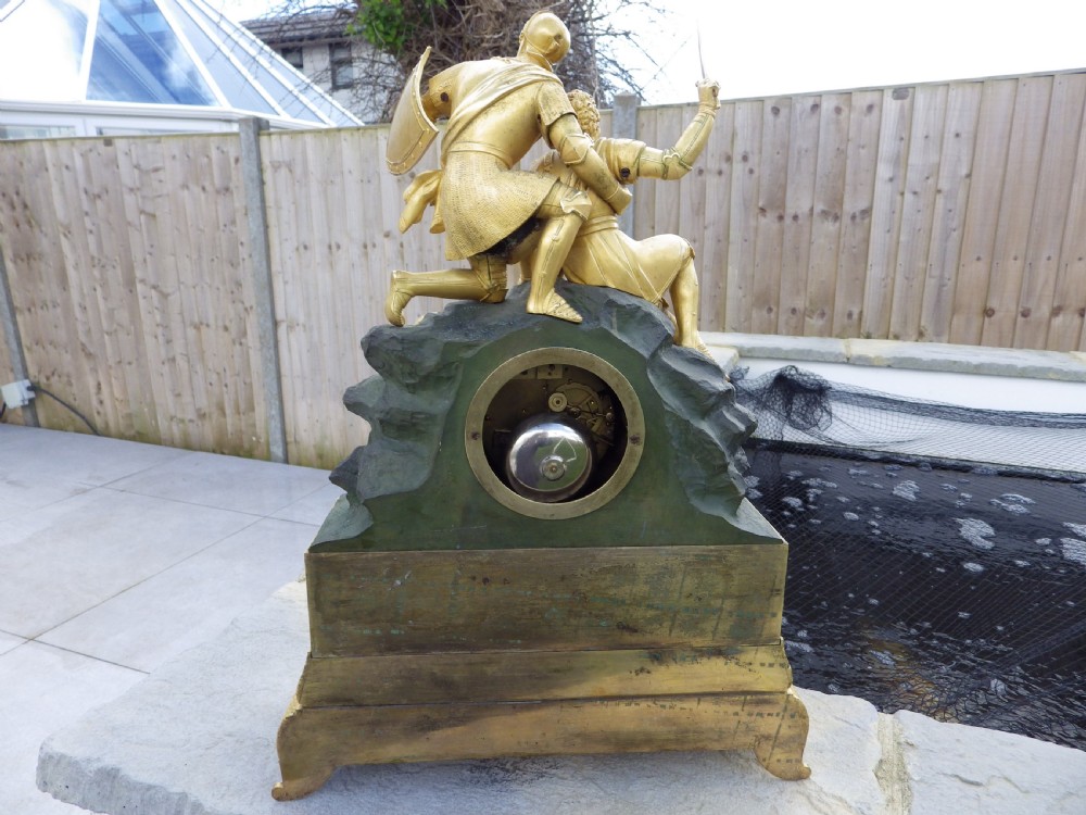 An antique French Empire gilt and patinated bronze mantel clock featuring sculpted figures of medieval soldiers above an ornamented base. View VI