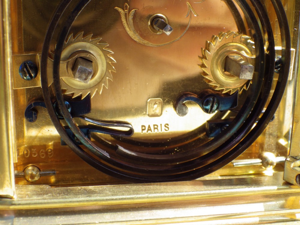 A late 19th-century French brass gorge case carriage clock with bevelled glass panels, a white enamel dial with Roman numerals, and a hinged brass carrying handle. View V