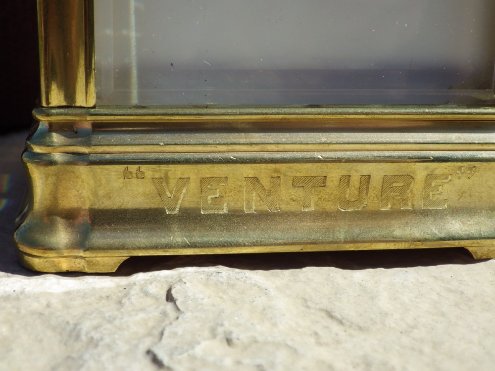 A late 19th-century French brass gorge case carriage clock with bevelled glass panels, a white enamel dial with Roman numerals, and a hinged brass carrying handle. View VII