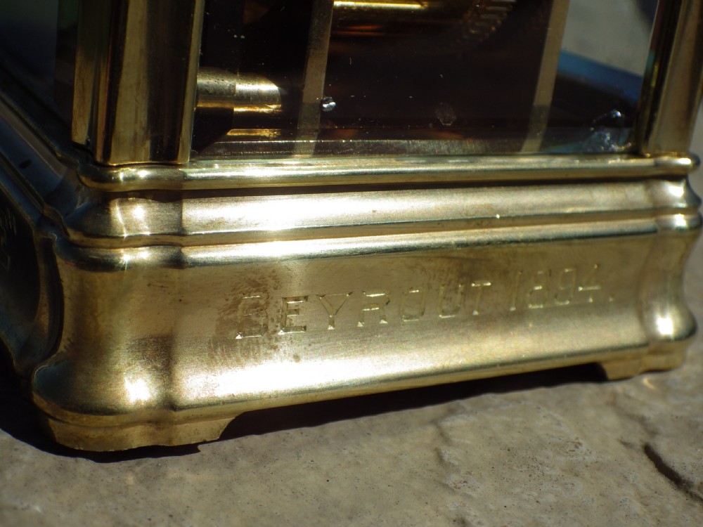 A late 19th-century French brass gorge case carriage clock with bevelled glass panels, a white enamel dial with Roman numerals, and a hinged brass carrying handle. View IX