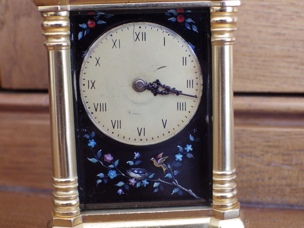 A French miniature gilt brass carriage clock featuring a stylized carrying handle, corner columns, and a black Limoges enamel face decorated with bird and floral painting. View VI