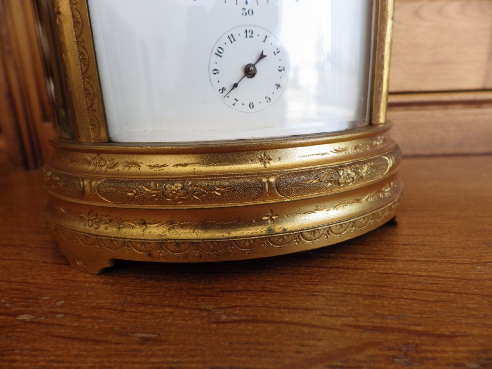 An antique 19th-century French oval gilt brass repeating carriage clock featuring a top carrying handle, glass panels, and a white enamel dial with Roman numerals. View II