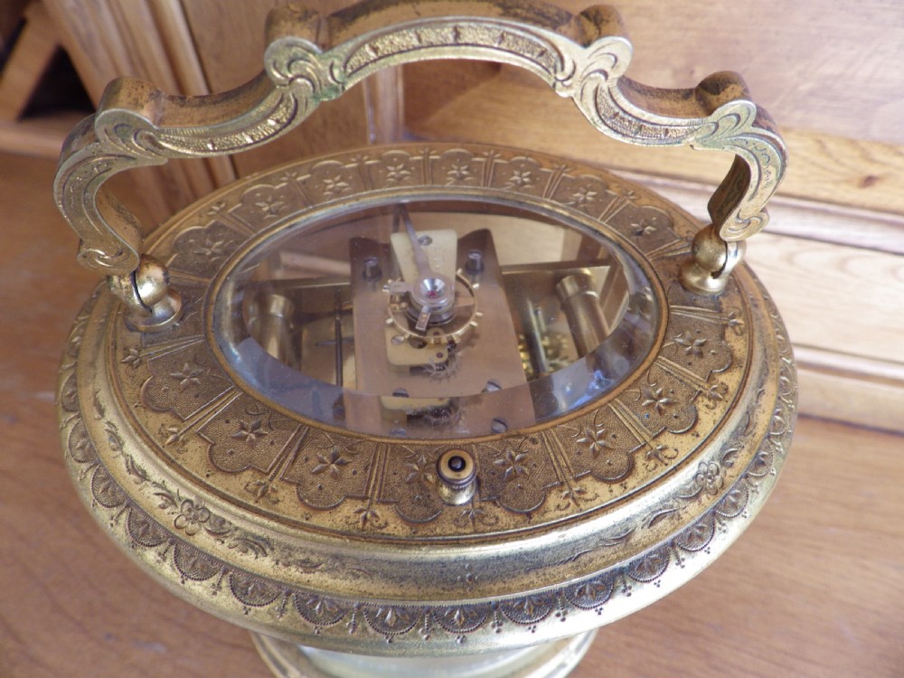An antique 19th-century French oval gilt brass repeating carriage clock featuring a top carrying handle, glass panels, and a white enamel dial with Roman numerals. View VI