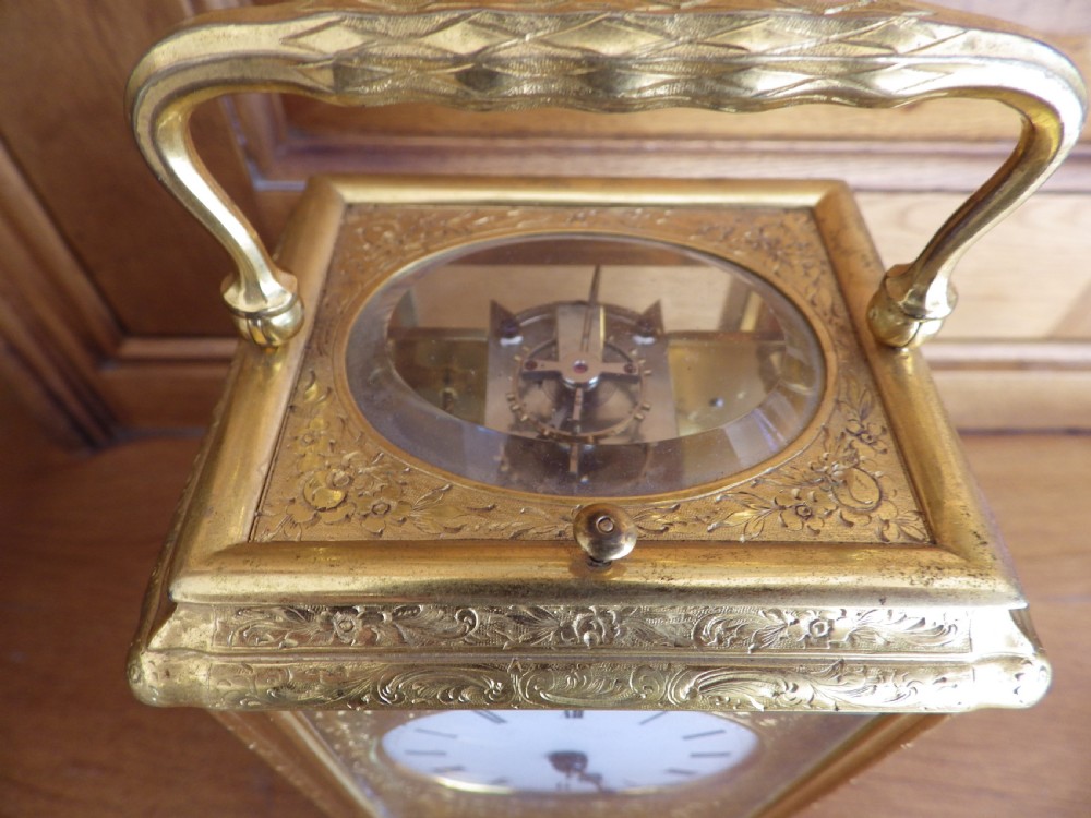 An engraved gilt brass French repeating carriage clock with a white enamel dial, Roman numerals, and a top handle. View VII