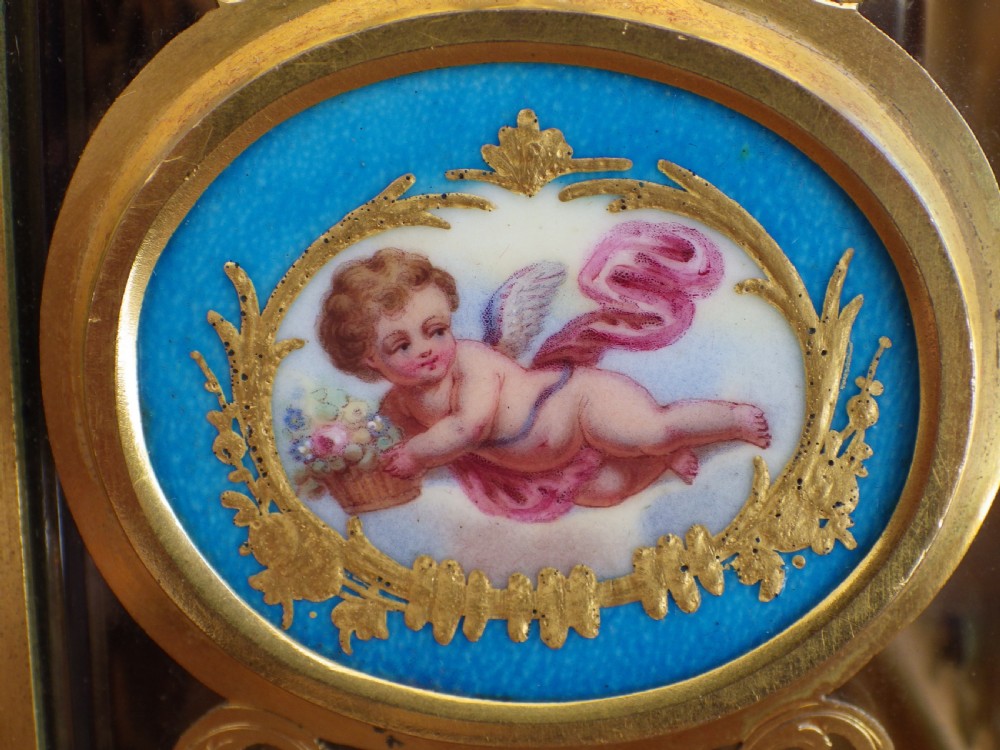 A French gilt brass carriage clock with an ornate foliate engraved face panel, white enamel dial with Roman numerals, secondary sub-dial, and decorative top handle. View VI