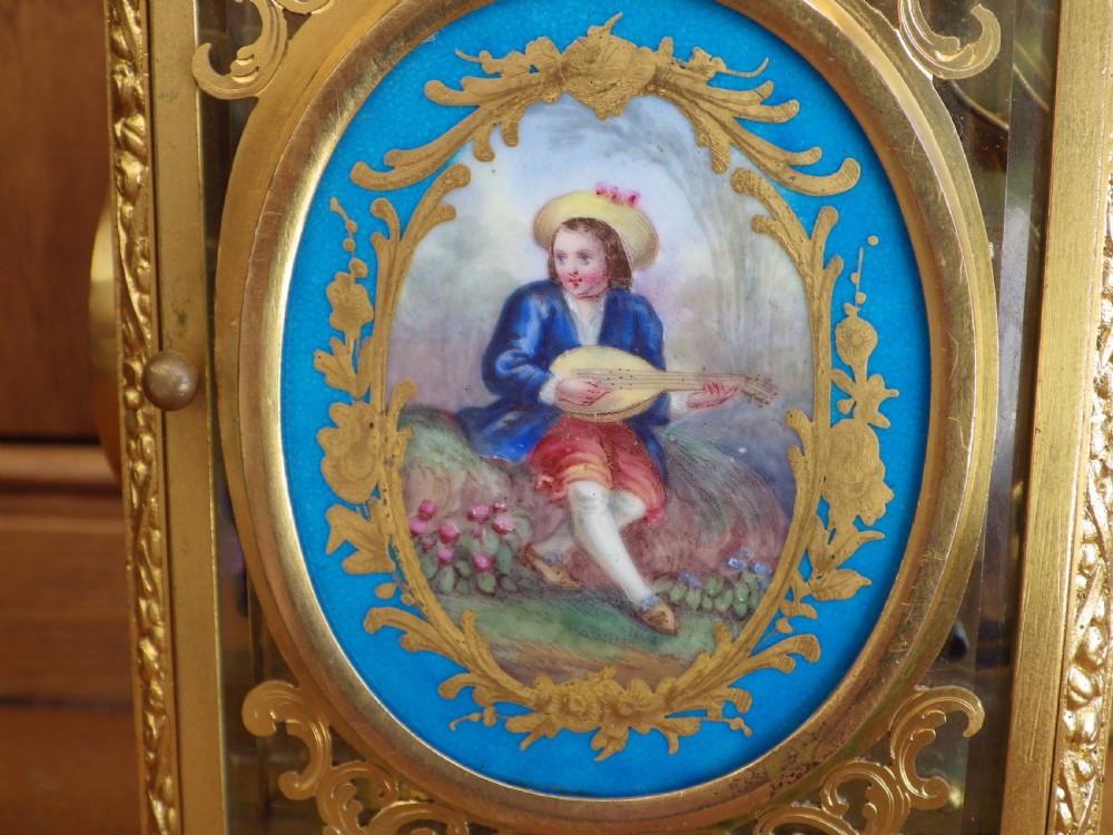 A French gilt brass carriage clock with an ornate foliate engraved face panel, white enamel dial with Roman numerals, secondary sub-dial, and decorative top handle. View VIII