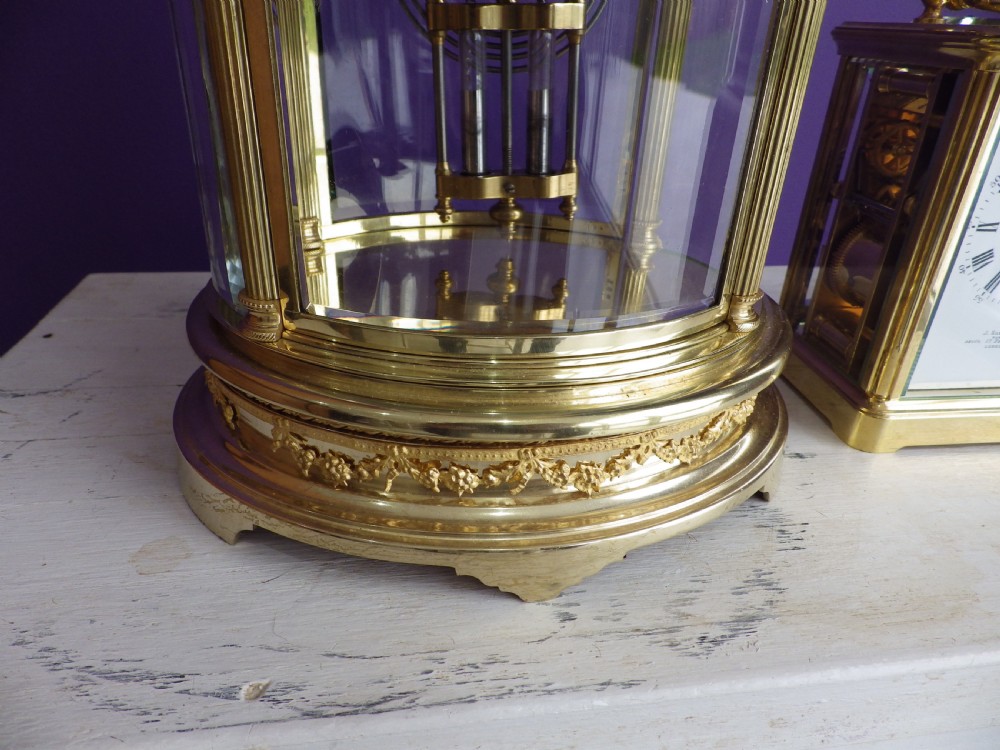 A French oval gilt brass crystal regulator clock featuring bevelled glass casing, fluted column supports, and an ornate circular dial. View II