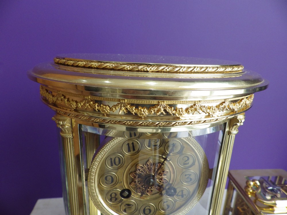 A French oval gilt brass crystal regulator clock featuring bevelled glass casing, fluted column supports, and an ornate circular dial. View III