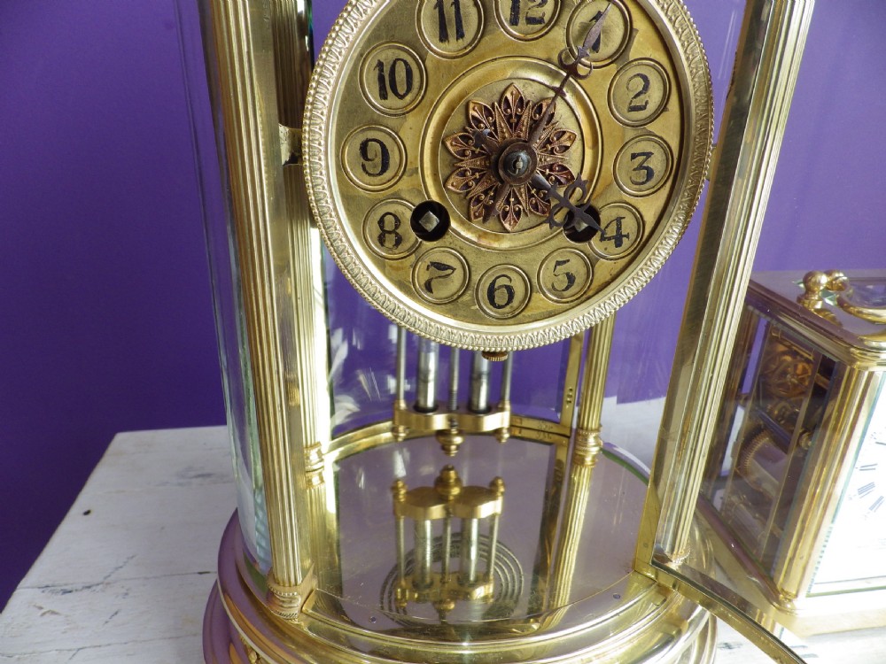 A French oval gilt brass crystal regulator clock featuring bevelled glass casing, fluted column supports, and an ornate circular dial. View IV
