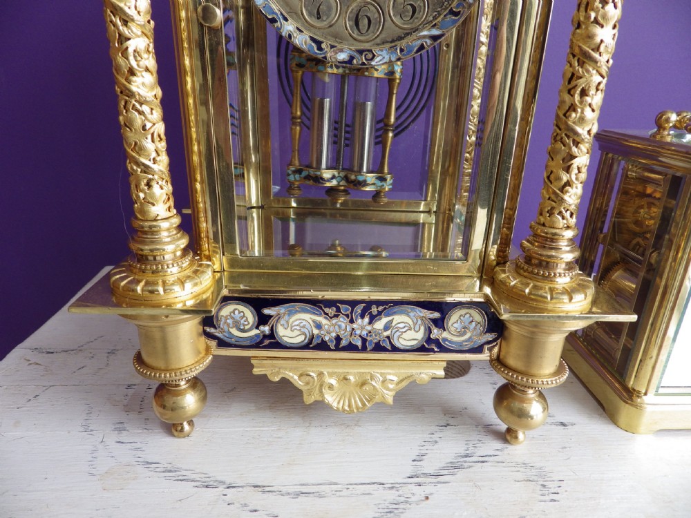 An antique French gilt brass crystal regulator clock featuring four clear glass sides, blue champleve enamel scrollwork, decorative corner columns, and an intricate dial. View II