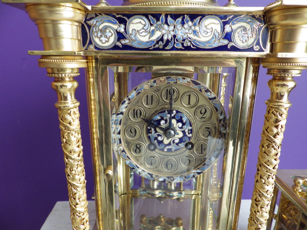 An antique French gilt brass crystal regulator clock featuring four clear glass sides, blue champleve enamel scrollwork, decorative corner columns, and an intricate dial. View III