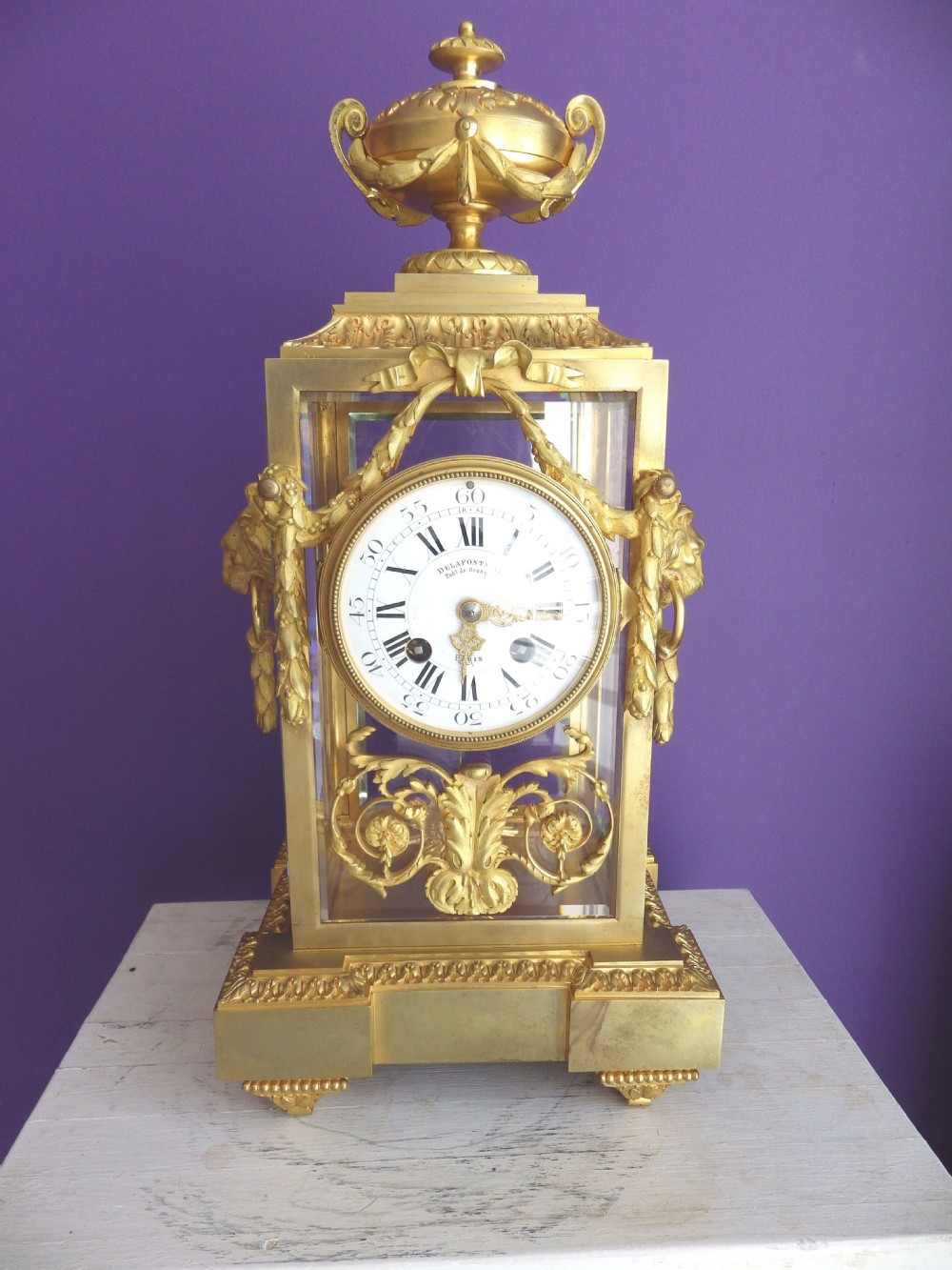 Late 19th-century French gilt bronze crystal regulator clock with bevelled glass sides, top urn finial, and white enamel dial.