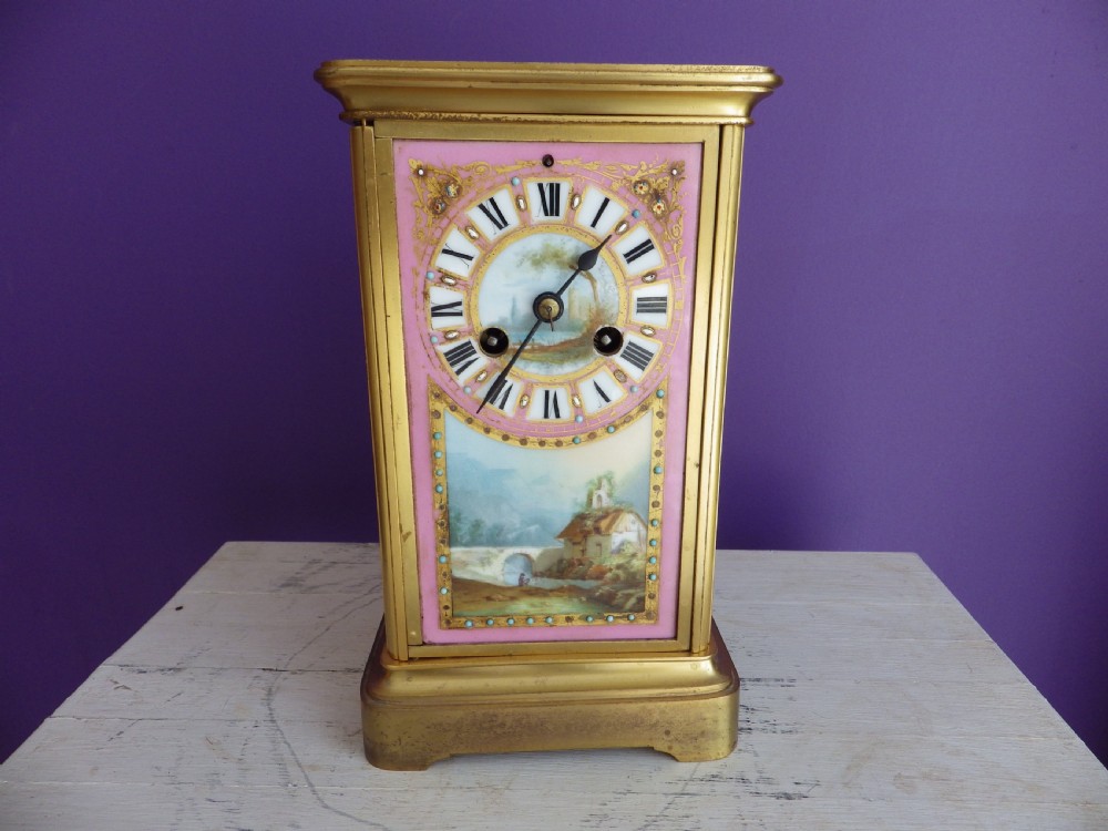 A nineteenth-century French gilt brass mantel clock featuring pink hand-painted porcelain panels depicting a landscape scene.